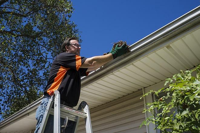 worker repairing damaged gutter on a residential roof in Burrillville